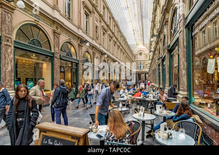 Die Menschen sitzen draußen Kaffee in einem Café in Les Galeries Royales Saint-Hubert, einem eleganten verglaste Einkaufspassage in Brüssel, Belgien Stockfoto