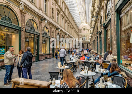 Die Menschen sitzen draußen Kaffee in einem Café in Les Galeries Royales Saint-Hubert, einem eleganten verglaste Einkaufspassage in Brüssel, Belgien Stockfoto