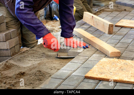 Der Arbeitnehmer Ebenen der Plattform für die Verlegung von Platten mit Hilfe einer Kelle und Holz- Bars, Abstimmung der IT auf die Ebene der gespannt. Stockfoto