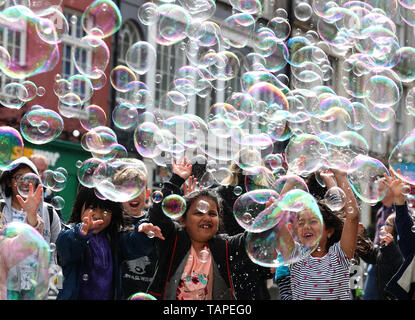 Kinder versuchen, Blasen von einer Straße Interpret auf Feiertag Montag zu verfangen, entlang der der Royal Mile in Edinburgh. Stockfoto