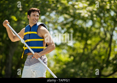 Lächelnd im mittleren Alter Mann Paddle Boarding. Stockfoto