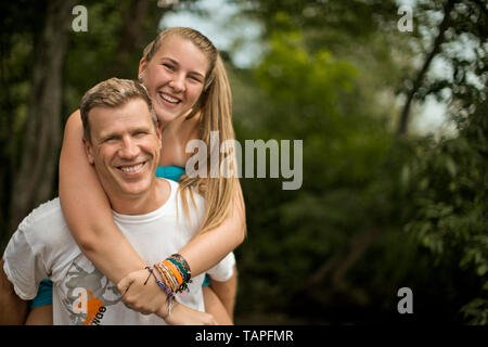 Porträt eines lächelnden im mittleren Alter Mann, der seine Tochter eine piggyback Ride. Stockfoto
