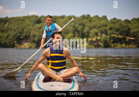 Vater und Sohn Spaß paddleboarding auf dem Fluss. Stockfoto