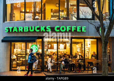 Kumamoto. Nachtleben und Shopping Arkade. Menschen innerhalb und außerhalb von Starbucks Coffee Shop sitzen. Abend mit Gebäude beleuchtet. Stockfoto