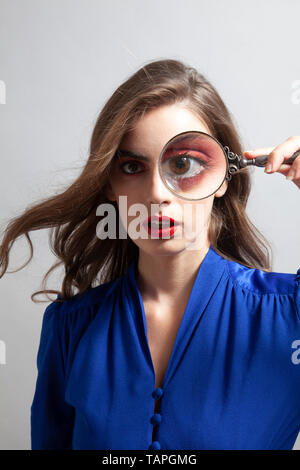 Frau mit Lupe über Auge Stockfoto