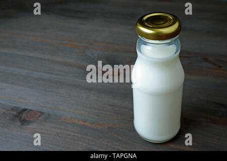 Glas Flasche voll Milch auf dunklen Holztisch mit Kopie Raum isoliert Stockfoto