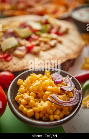 Schließen bis auf Mais Saatgut mit verschiedenen frisch zubereitete Mexikanische Lebensmittel Sortiment in den Rücken. Auf bunten Tisch gelegt. Mit Nachos, Tacos, Tortillas, Kühlergrill Stockfoto