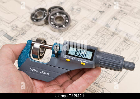 Kugellager Messung. Mikrometerschraube Manometer in der menschlichen Hand. Digitale Anzeige auf präzisen Messgerät. Technischer Hintergrund. Gruppe von Metallteilen. Stockfoto