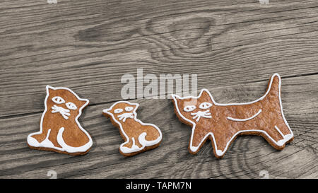 Cute gebackene Lebkuchen Süßigkeiten. Cat Formen auf Holz Hintergrund. Drei aromatischen Cookies eingerichtet durch Vereisung. Kunstvoll bemalte Weihnachten oder Neujahr Gebäck. Stockfoto