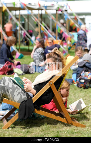 Hay Festival, Heu auf Wye, Powys, Wales, Großbritannien - Montag, 27. Mai 2019 - Besucher genießen eine Chance auf dem Festival Rasen zwischen Ereignissen und Lautsprecher im Hay Festival auf einem sonnigen, aber kalten breezy Feiertag Montag zu lesen. Foto Steven Mai/Alamy leben Nachrichten Stockfoto