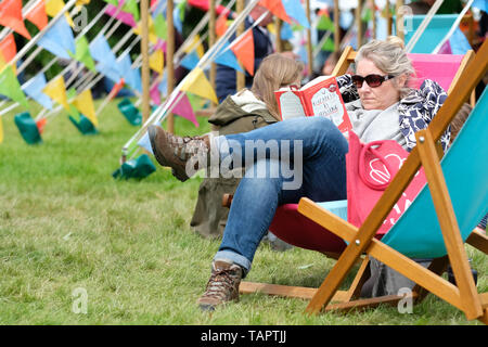 Hay Festival, Heu auf Wye, Powys, Wales, Großbritannien - Montag, 27. Mai 2019 - ein Besucher genießt eine Chance auf dem Festival Rasen zwischen Ereignissen und Lautsprecher an der Hay Festival an einem kühlen sonnigen breezy Feiertag Montag zu lesen. Foto Steven Mai/Alamy leben Nachrichten Stockfoto