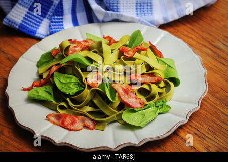 Grüne Spinat Nudeln mit chrispy Speck auf Holztisch. Gourmet Italienisch essen Stockfoto