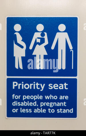 Priorität Sitz für Behinderte, Schwangere oder weniger in der Lage, Zeichen auf einer Londoner Bahnhof zu stehen Stockfoto