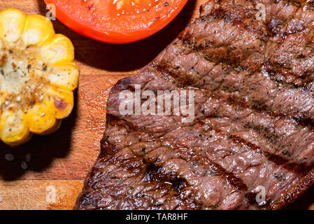 In der Nähe von frisch gegrilltes Steak auf Holz mit Tomaten und Mais Stockfoto