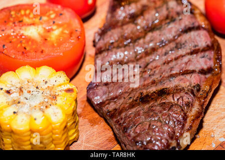 In der Nähe von frisch gegrilltes Steak auf Holz mit Tomaten und Mais Stockfoto