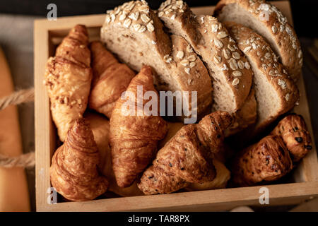 Schließen Sie Getreide Brot geschnitten und Croissant auf dem hölzernen Tisch Stockfoto