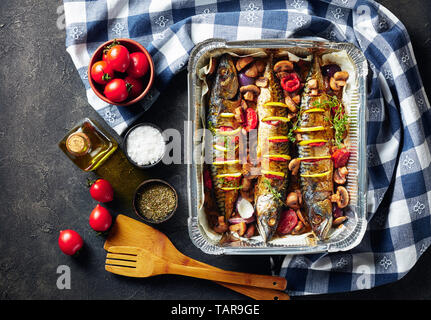 Drei ganze gegrillte Makrele mit Zitronen, Tomaten, Pilze, Gewürze und Kräuter. scomber gebacken in Aluminium Backform mit Pilzen und Tomaten, Hori Stockfoto