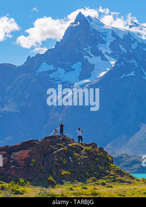 Vertikale Foto von drei Touristen mit Blick auf die Anden Gipfel des Paine Massivs und Pehoe See, Torres del Paine Nationalpark, Patagonien, Chile. Stockfoto