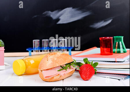 Schule Mittagessen auf dem Tisch und einer Tafel für eine Lektion. Kinder- sandwich Frühstück, Saft und Obst. Freier Platz für Text. Platz kopieren Stockfoto