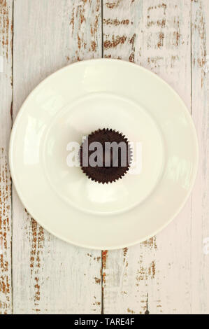 Braun chocolate Cupcakes mit cremefüllung auf einem weißen Teller auf dem Tisch mit schäbigen Boards Stockfoto