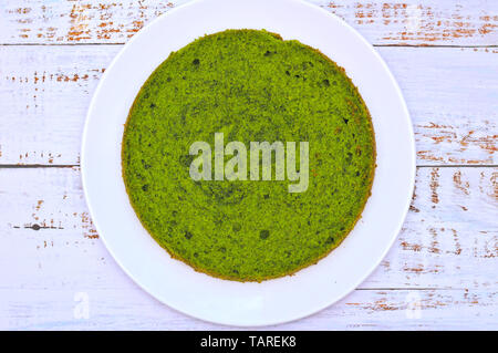 Grüne runde Spinat mint Kuchen auf einem weißen Teller auf dem Tisch mit schäbigen Boards Stockfoto