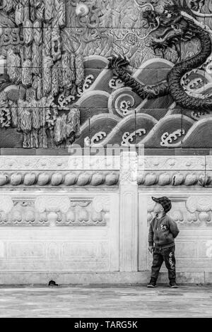 Einen kleinen chinesischen Jungen vor der schönen Drachen in der Verbotenen Stadt in Peking, China, posing Stockfoto