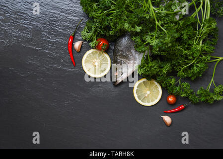 Frischer Wolfsbarsch Fisch für das Kochen mit Kräutern und Gewürzen Zitronen Tomaten chili curly Petersilie Ozean Knoblauch gourmet Abendessen/roher Fisch Meeresfrüchte Wolfsbarsch in der Stockfoto