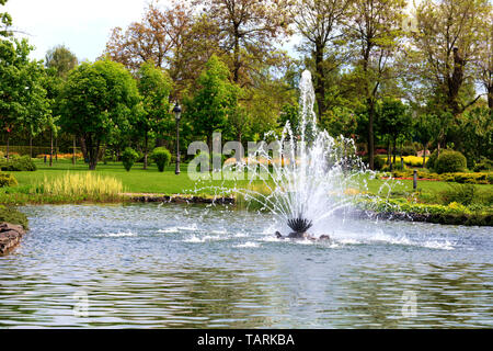 Einen schönen Brunnen in der Mitte der Feder Teich vor dem Hintergrund der malerischen Stadt park, grünen Wiesen und blühenden Kastanien. Stockfoto