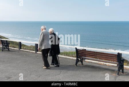 Ältere Paare zu Fuß entlang der Promenade overloking das Meer. Großbritannien Stockfoto