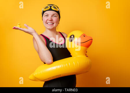 Photo of happy woman in bathing suit with life preserver on empty orange background in studio Stockfoto