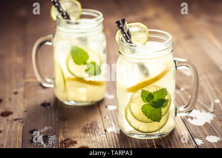 Kalten frischen Mojito Cocktail Limonade mit Eis, Zitrone und Minze in Mason Jar auf rustikalen dunklen Hintergrund. Sommer Konzept. Stockfoto
