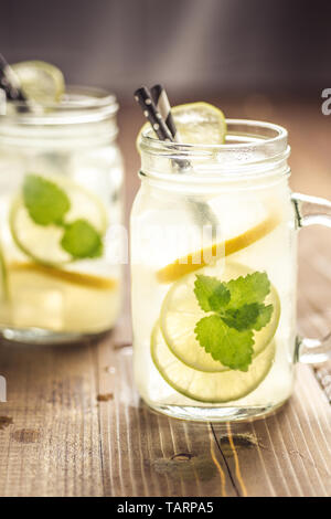 Kalten frischen Mojito Cocktail Limonade mit Eis, Zitrone und Minze in Mason Jar auf rustikalen dunklen Hintergrund. Sommer Konzept. Stockfoto