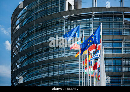 Fassade des Europäischen Parlaments mit Fahnen aller Mitgliedstaaten der Europäischen Union winken bei ruhigem Wind am Tag der Wahlen zum Europäischen Parlament 2019 Stockfoto