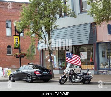 Eine amerikanische Flagge ist der Hintergrund für diese Harley Davidson Motorrad auf der Straße von einem kleinen Oregon Stadt geparkt. Stockfoto