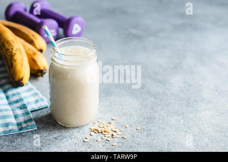 Protein Milchshake oder Smoothie mit Banane und Hafer im Glas auf konkrete Tabelle. Kopieren Sie Platz. Sportlich, Fitness, gesunder Lebensstil Konzept Stockfoto