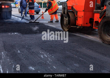 Die Textur und den Hintergrund des neuen frisch gelegte Asphalt vor dem Hintergrund der Bau team Road Service- und Baumaschinen. Stockfoto