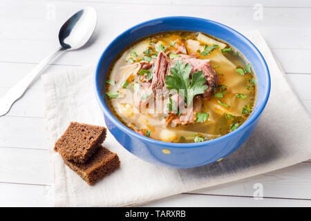 Russische traditionelle Kohlsuppe mit Fleisch und frischen Kräutern auf einem Leuchttisch Stockfoto