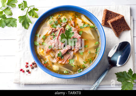 Russische traditionelle Kohlsuppe mit Fleisch und frischen Kräutern auf einem Leuchttisch Stockfoto