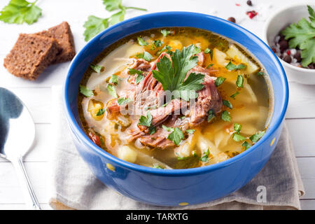 Russische traditionelle Kohlsuppe mit Fleisch und frischen Kräutern auf einem Leuchttisch Stockfoto