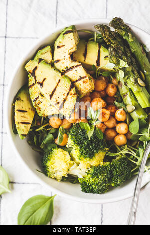 Buddha Schüssel mit gegrillten Avocado, Spargel, Erbsen, Kichererbsen, Sprossen und Brokkoli. Veganes essen Konzept. Stockfoto