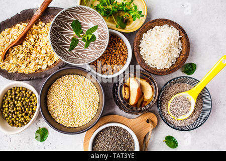 Flach von superfoods und Getreide Auswahl in Schalen - Reis, Chia Samen, Nüssen, Haferflocken, Buchweizen, Quinoa, Mung Bohnen und Grüns auf einem weißen backgroun Stockfoto