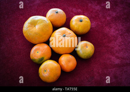 Stapel von orange Frucht rot verschiedene Größen auf dunklem Hintergrund Stockfoto