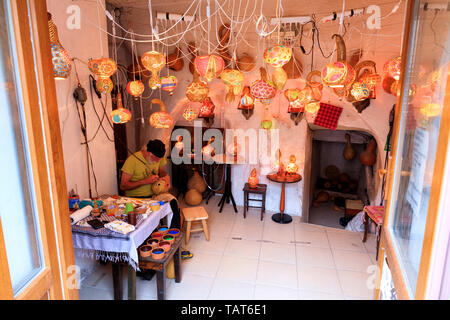 Eines Alten Meisters macht traditionelle orientalische Lampen aus getrockneten Kürbissen, sie dekorieren mit einem bunten Glas Ornament. Stockfoto