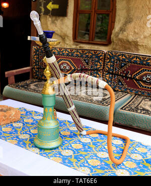 Shisha steht auf dem Tisch an einem wunderschönen weißen und blauen Tischdecke mit orientalischen Ornamenten in eine alte Hütte auf dem Hintergrund einer unscharfen Innenraum Stockfoto