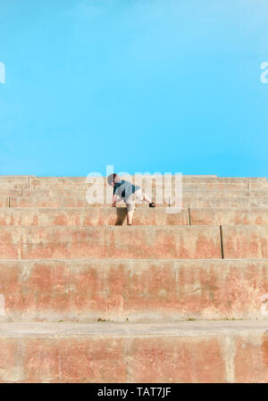 Ein junges Kind klettert sehr große Schritte in Richtung einer klaren blauen Himmel. Stockfoto