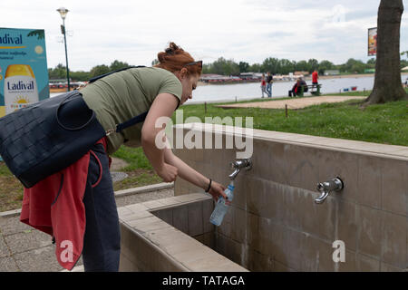 Belgrad, Serbien, 12. Mai 2019: Frau füllt am öffentlichen Brunnen Ada Ciganlija eine Flasche Wasser Stockfoto