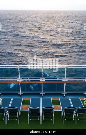 Blaue Liegestühle auf dem Grün Deck des Schiffes mit Blick auf das Meer und die Wellen. Stockfoto