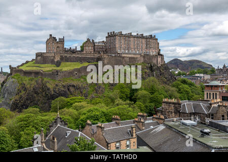 Blick über die Dächer in Richtung Edinburgh Castle in Schottland. Mit dem antiken Hügel fort von Arthur's Seat im Hintergrund. Stockfoto