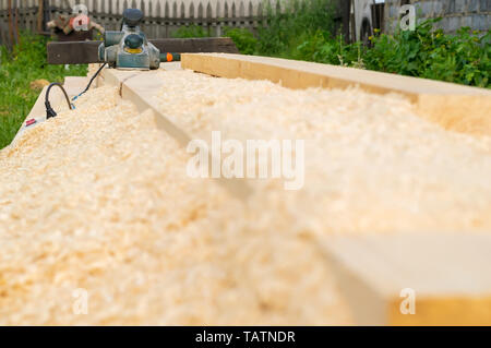 Elektrische Werkzeuge für die Holzbearbeitung liegen auf dem Holz im Freien Stockfoto