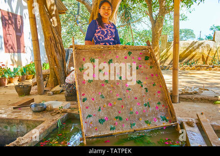 PINDAYA, MYANMAR - 19. FEBRUAR 2018: Das Porträt der jungen Handwerker, die natürlichen ökologischen Shan Papier des Maulbeerbaumes Teig mit Blütenblättern Stockfoto